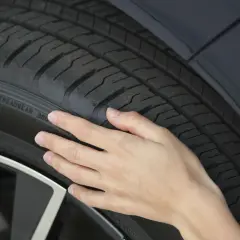 Dłoń dotyka bieżnika opony, pokazując napis "TREADWEAR". To jeden ze sposobów, jak sprawdzić rok opony, choć tu widzimy tylko oznaczenie zużycia.