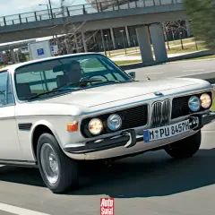 Białe BMW E9 3.0 CS z lat 70. sunie po drodze, jego klasyczna linia zachwyca.
