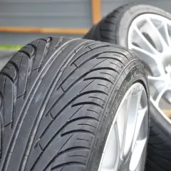 Dwa opony samochodowe na felgach, jeden bliżej, drugi dalej.