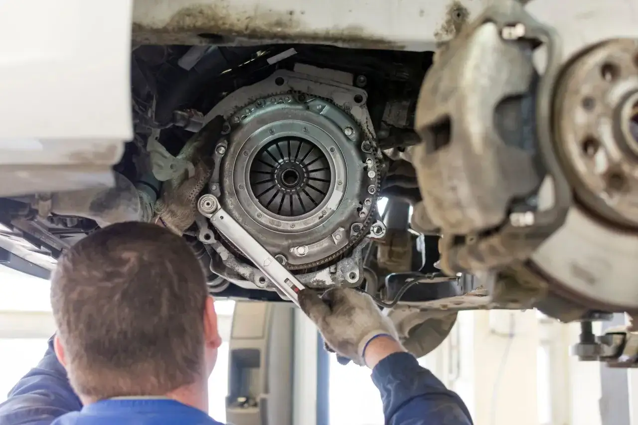 Mechanik dokręca śruby sprzęgła. Zastanawiasz się, ile kosztuje wymiana sprzęgła?