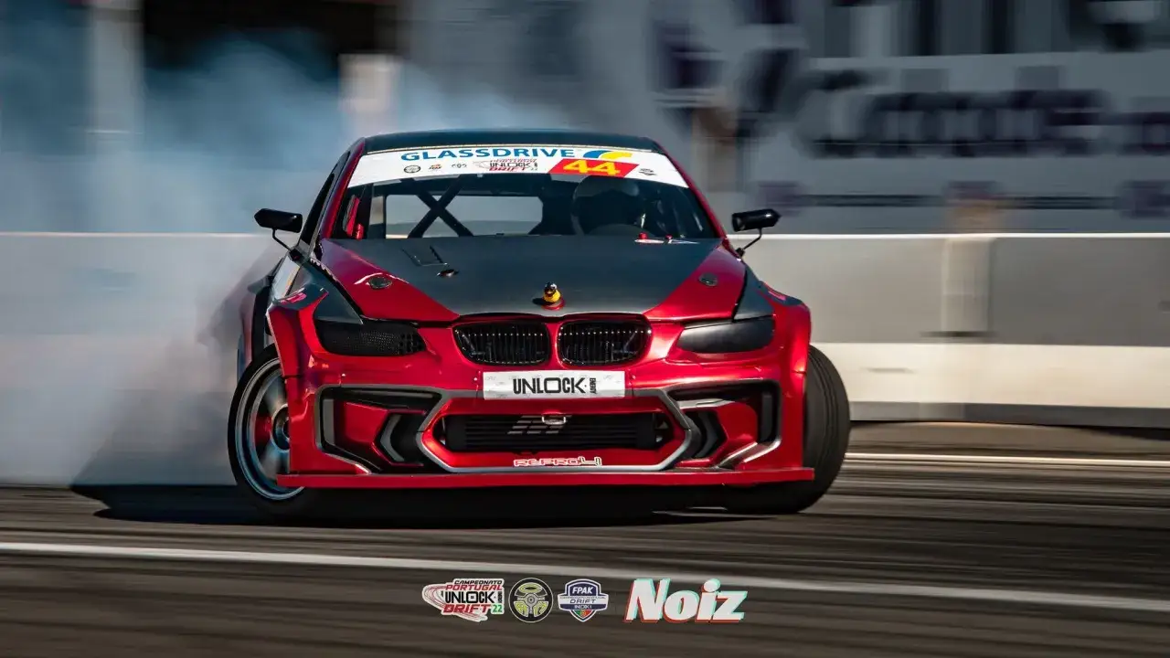 Czerwone BMW E92 335is w akcji driftu, z kłębami dymu unoszącymi się z opon.